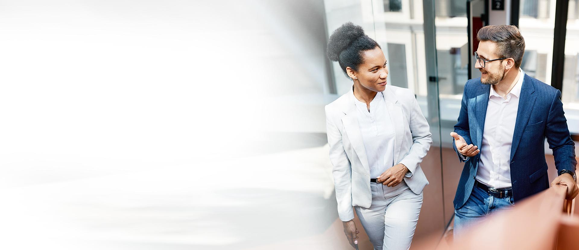 Eine Dame und ein Herr in Anzügen sprechen miteinander.